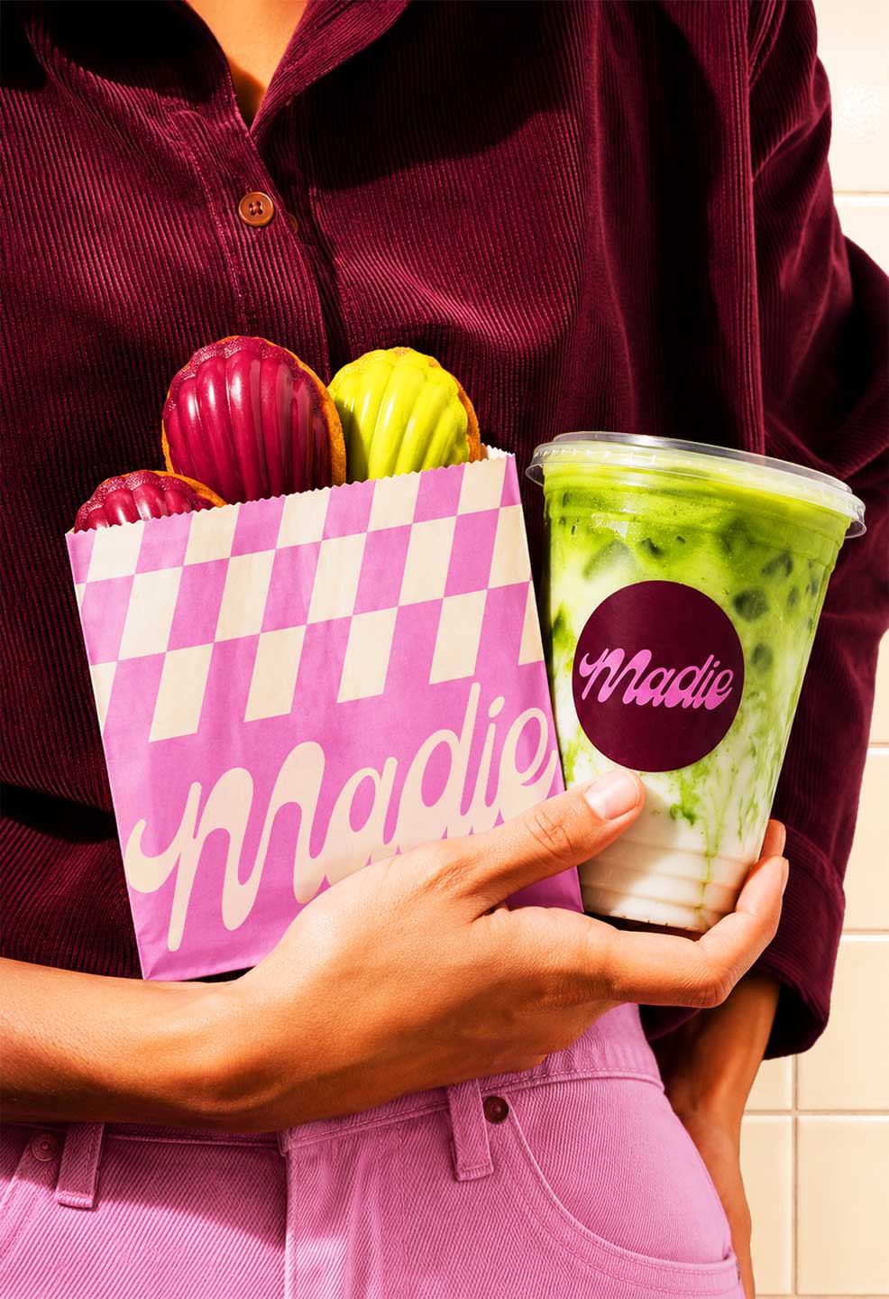 Box of colorful glazed madeleines on pink car hood