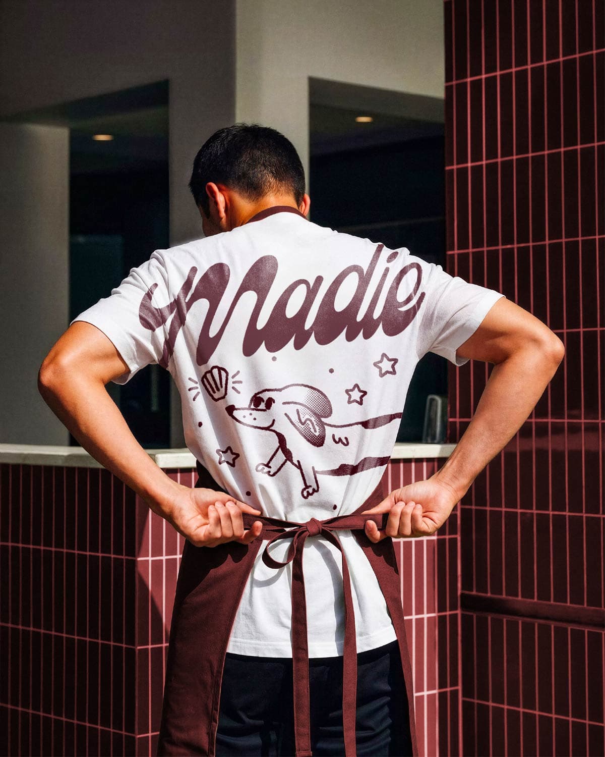 Barista tying apron in Madie branded uniform