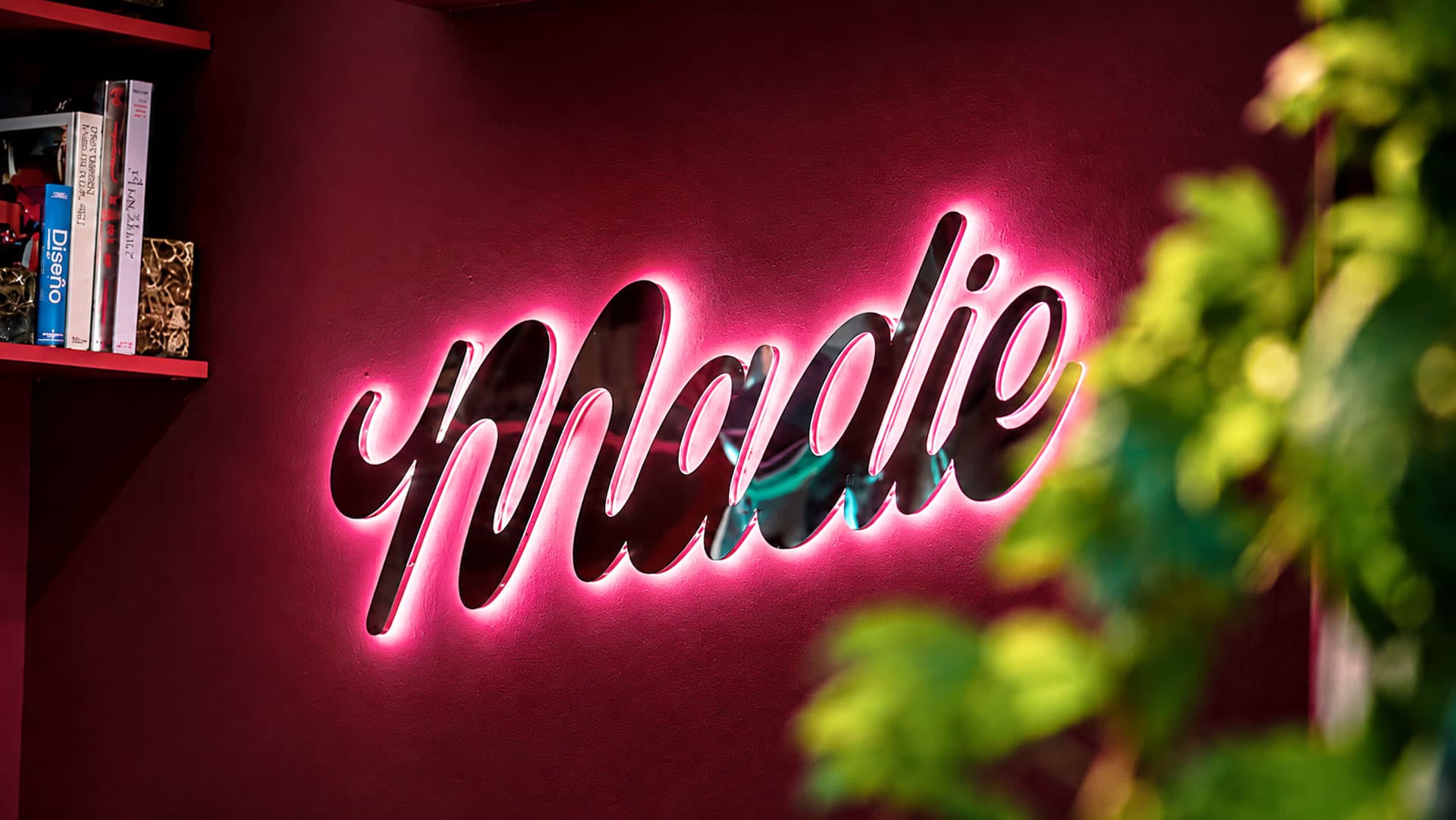 Glowing magenta neon Madie script on textured pink wall