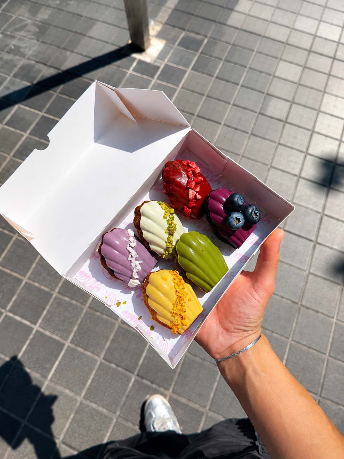 Hands holding open box of madeleines