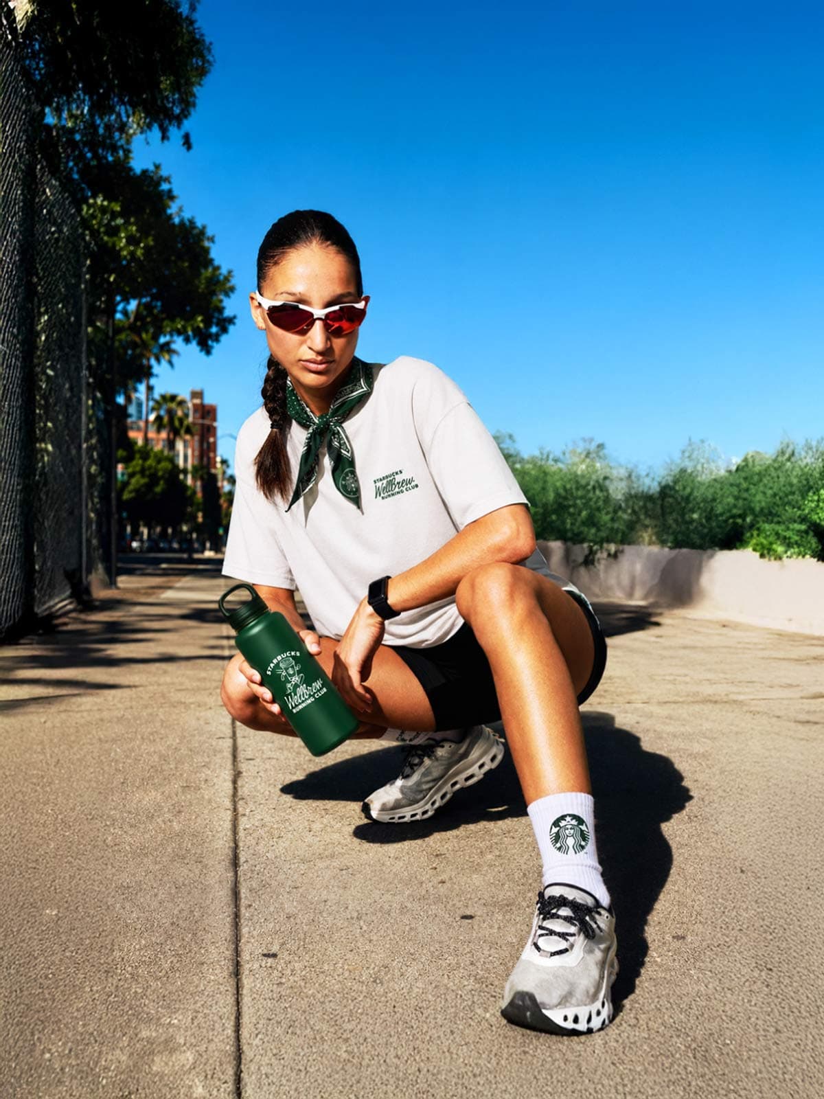 Female runner resting on curb with green Starbucks water bottle