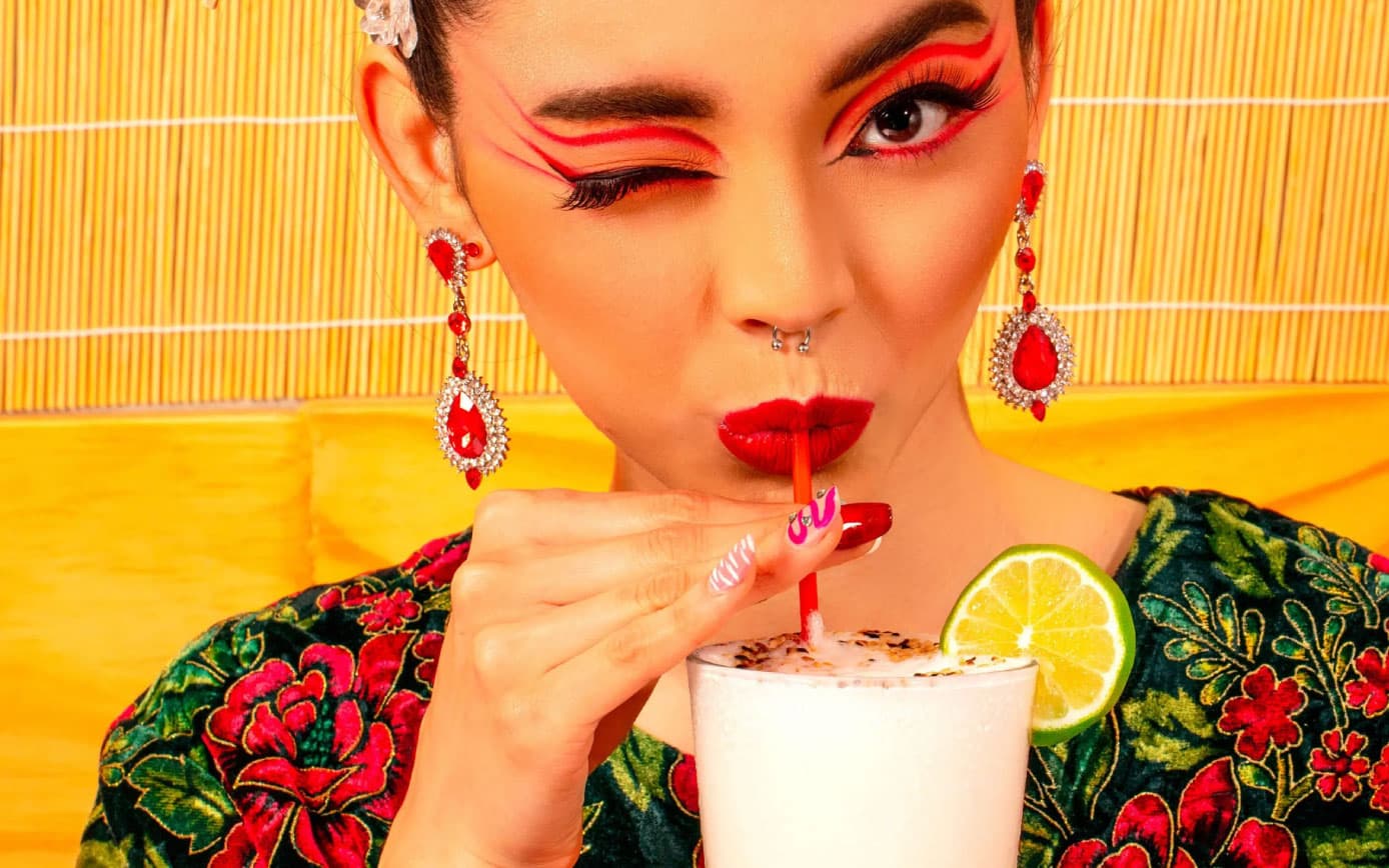 Model winking while sipping iced beverage