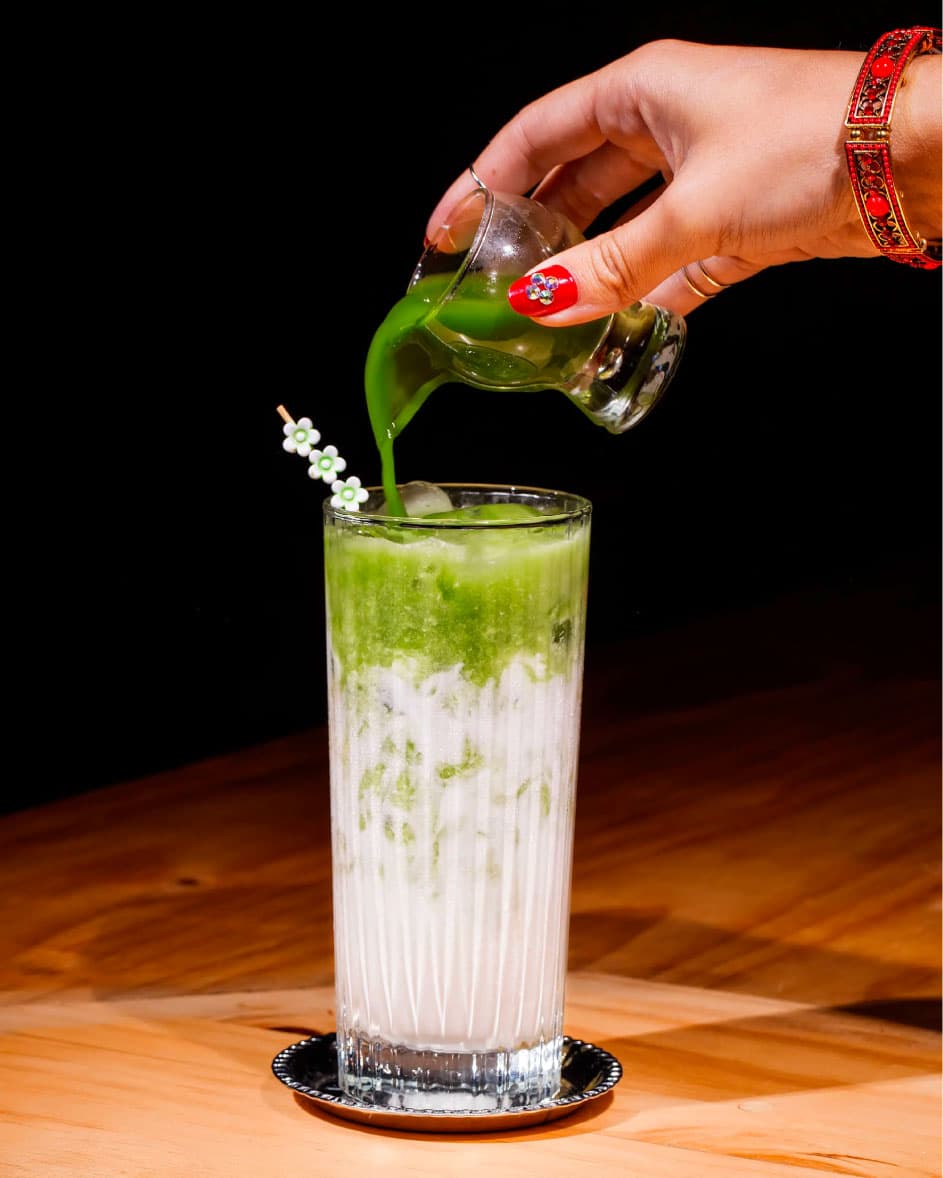 Pouring green matcha iced drink into glass